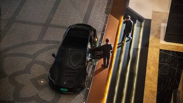 A black car parked at a hotel entrance with a sign reading 'GRANT FOURWELL.'