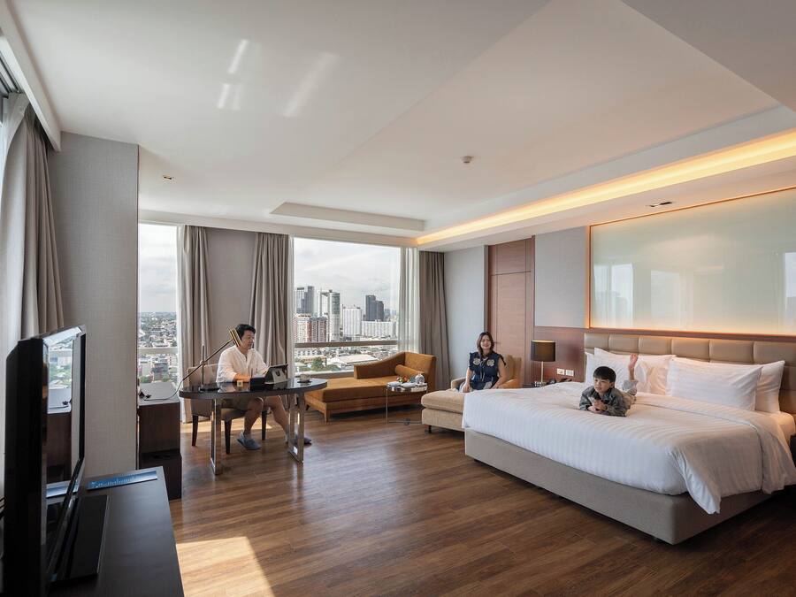 Una habitación de hotel moderna con una cama grande, un escritorio, un sofá y un televisor.