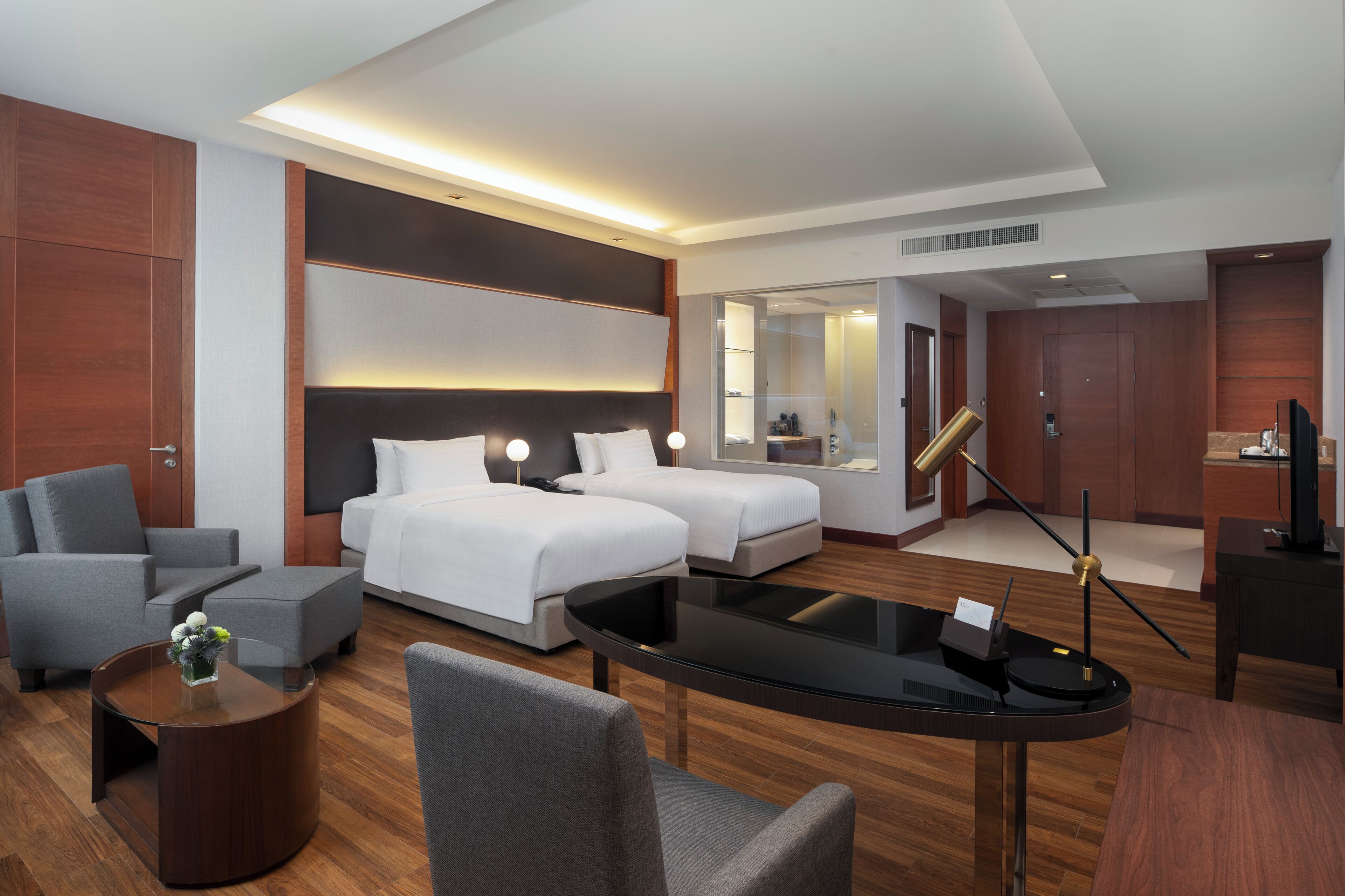 Una habitación de hotel con dos camas, un sofá, una mesa de centro y una televisión.