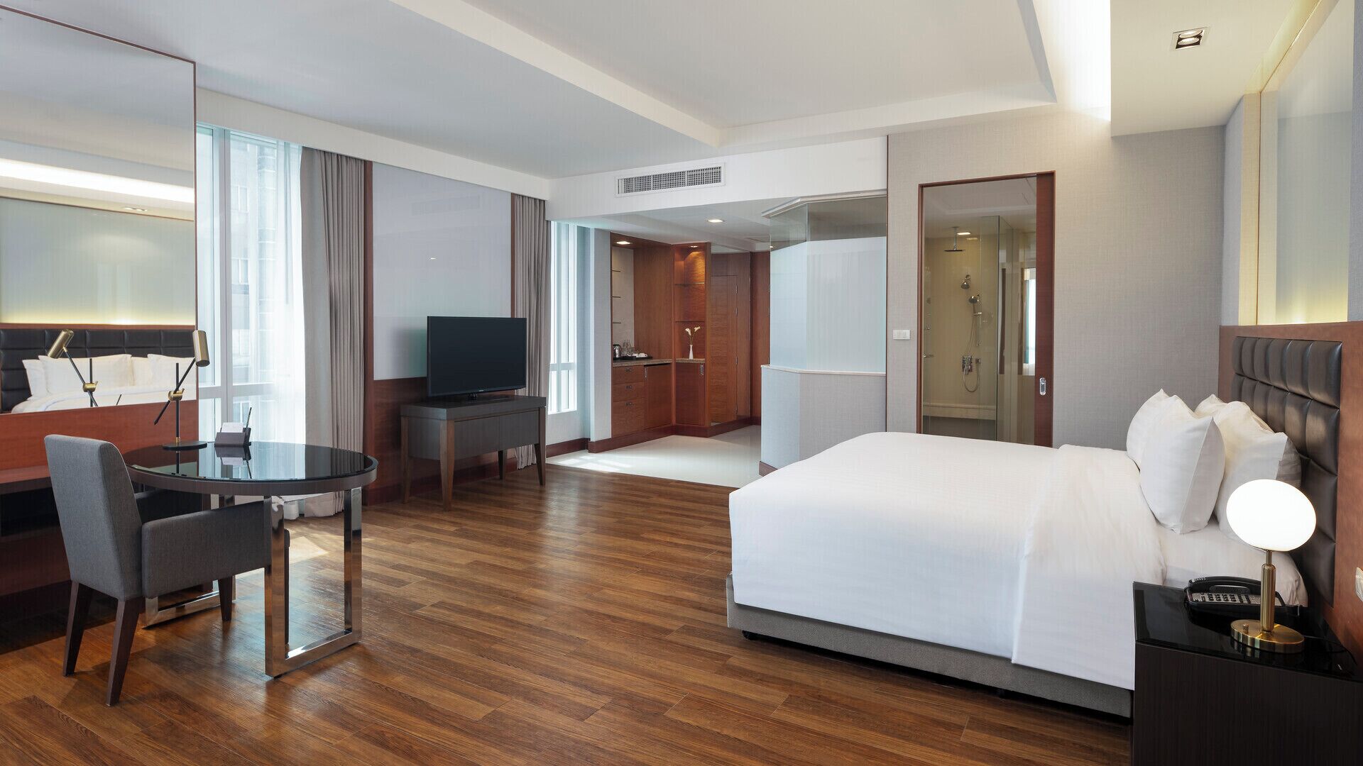 A hotel room with a bed, a desk with a chair, a television, and a bathroom.