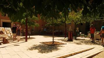 An outdoor area with a tiled floor, trees, and a small kiosk.