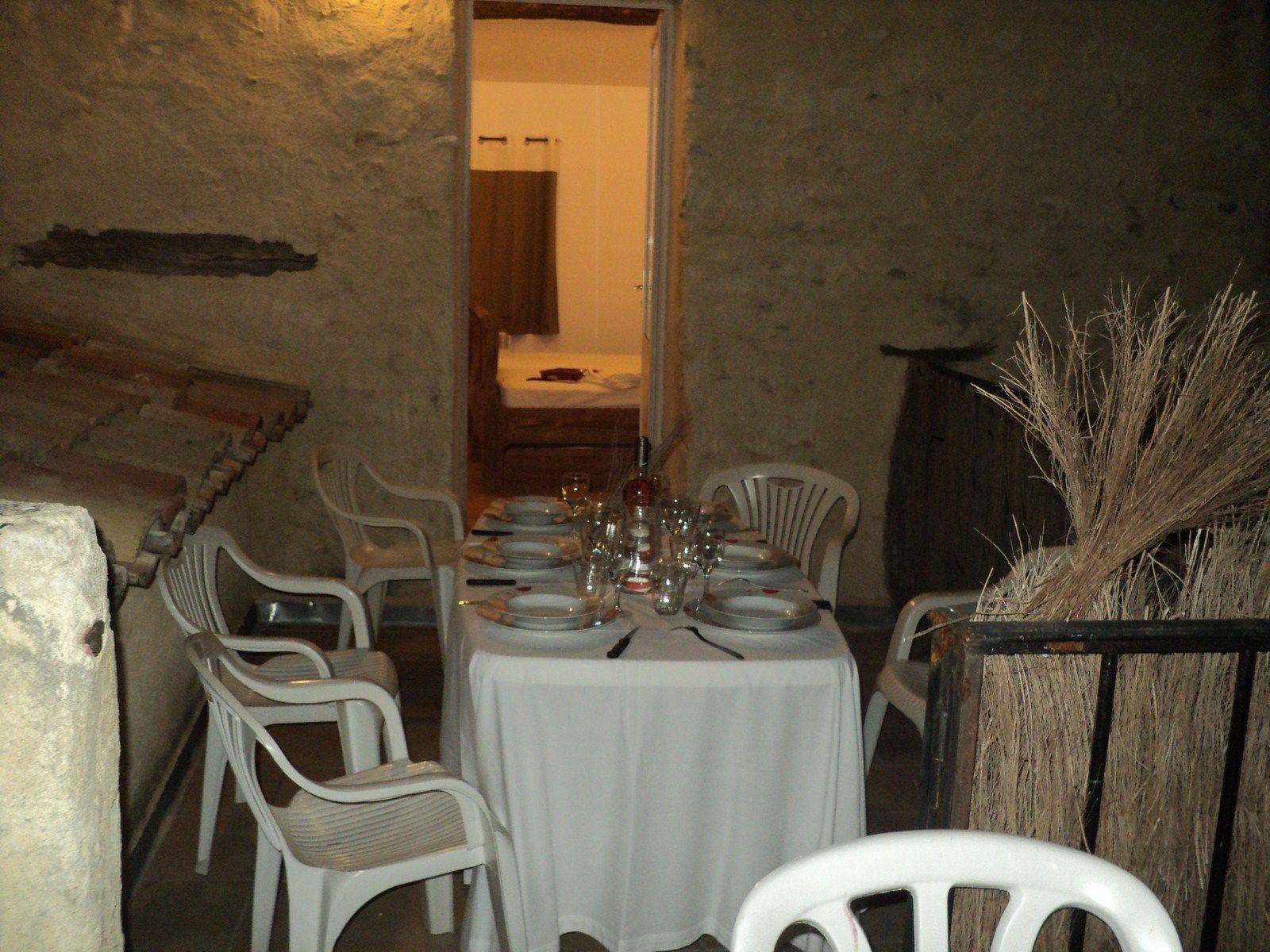 Un espace repas avec une table ronde dressée pour six personnes, entourée de chaises en plastique blanches.