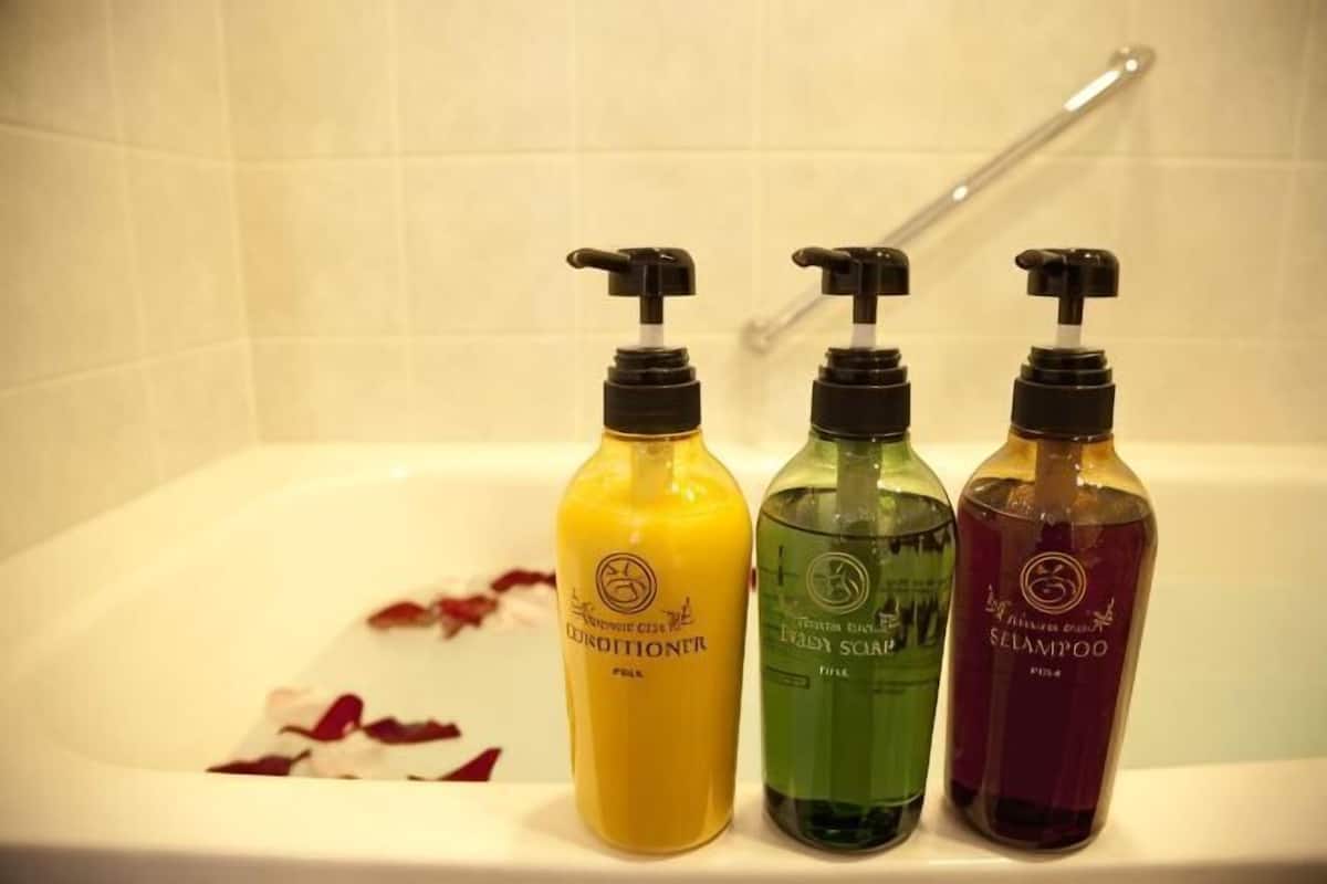 Three bottles of shampoo and conditioner on a bathtub.