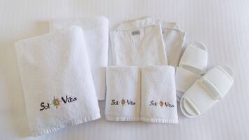 A set of white towels and slippers with embroidered text "Sol Vita" and a logo, arranged neatly on a white surface.
