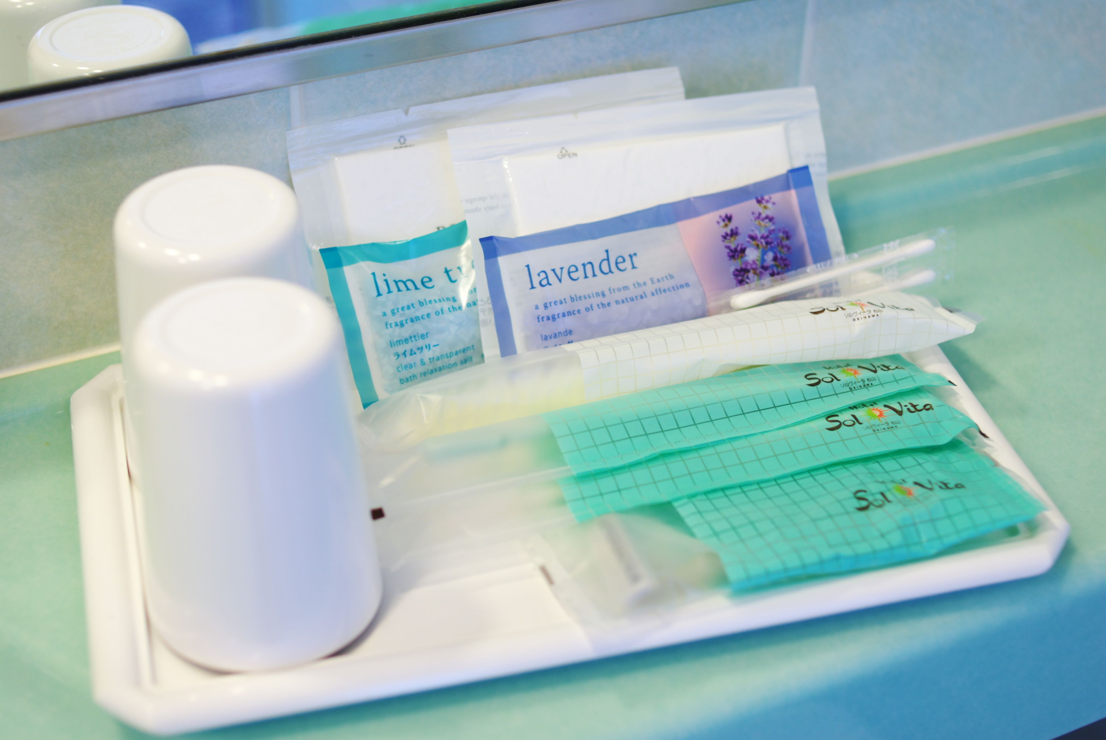 A tray with toiletries including a bottle of lime, a bottle of lavender, and several packets labeled 'Sol Vita'.