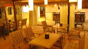A room with wooden furniture, including tables and chairs, and a thatched roof ceiling. - Koh Tao Toscana (Koh Tao)
