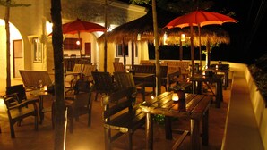 An outdoor dining area with wooden furniture and red umbrellas. - Koh Tao Toscana (Koh Tao)
