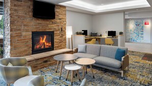 Un moderno vestíbulo de hotel con chimenea de piedra, zona de estar y mostrador de recepción.