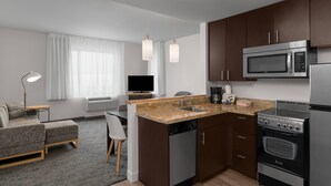 Una cocina moderna equipada con microondas, horno y lavavajillas. Hay un comedor con mesa y sillas, y un sofá en la sala de estar.