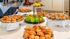 Un bufé con diversas opciones de comida, incluyendo pasteles, frutas y pan.