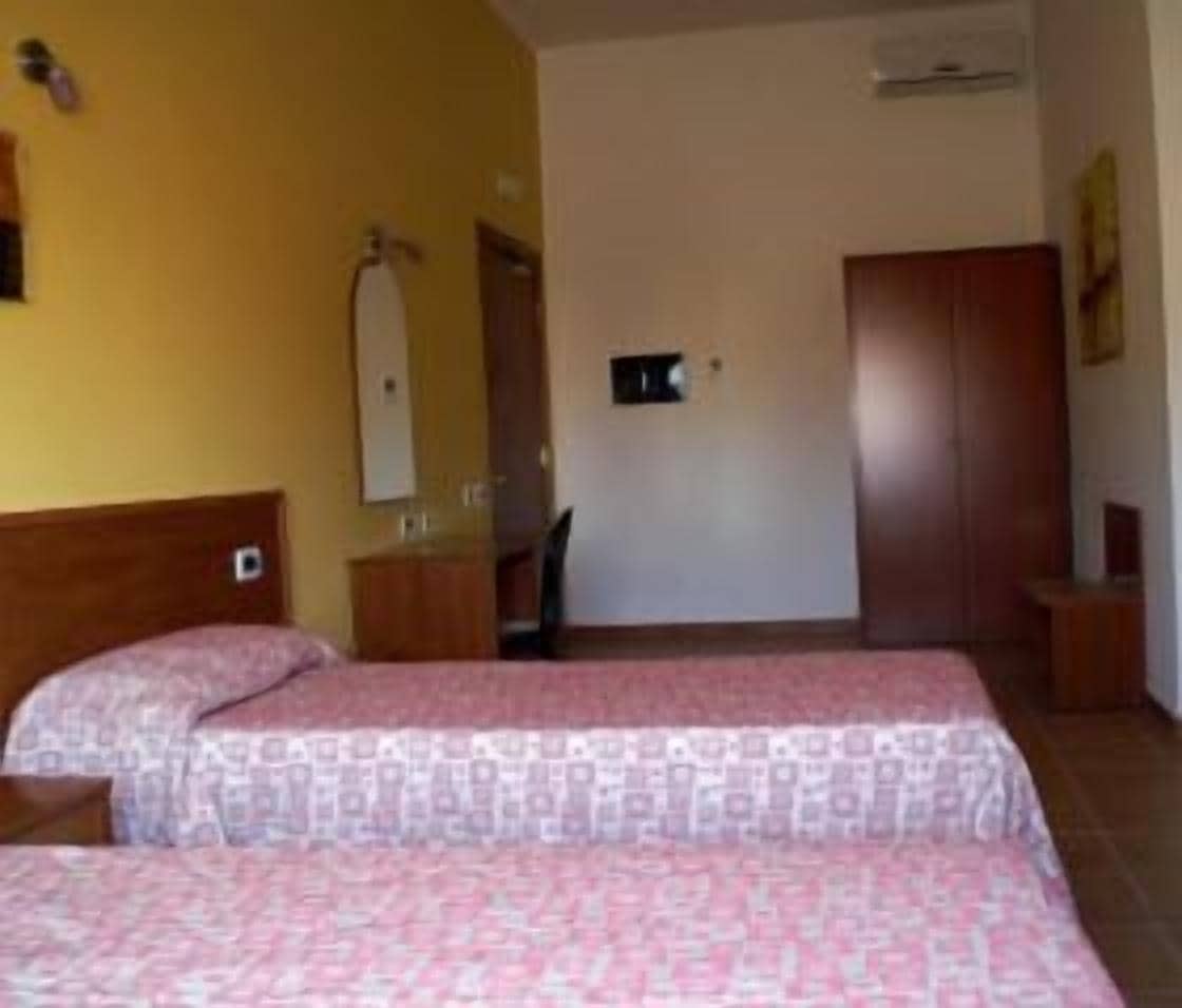 Une chambre d’hôtel avec deux lits, une armoire, un miroir et un petit bureau.