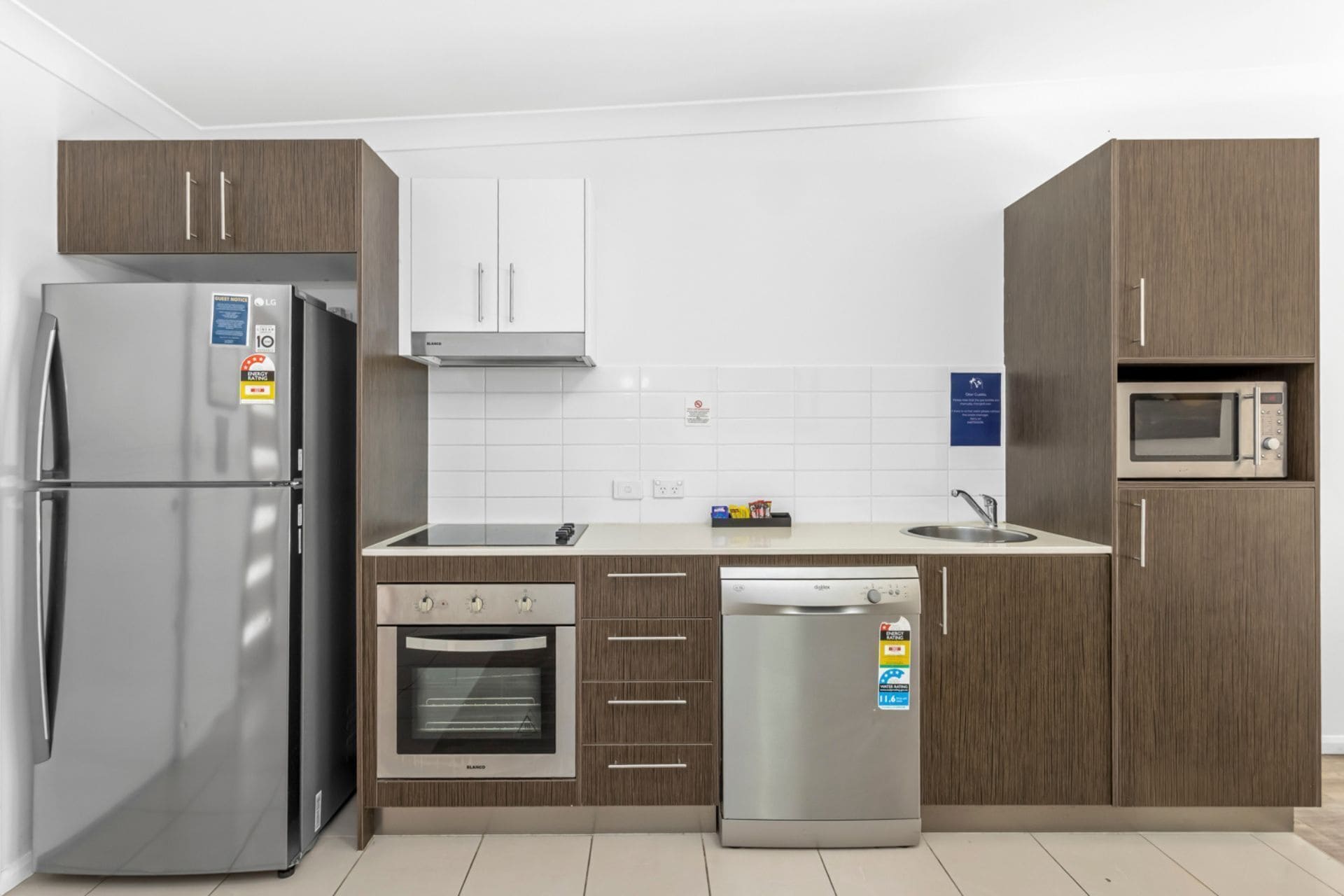 A modern kitchen with a stainless steel refrigerator, a built-in oven, a dishwasher, and a microwave.