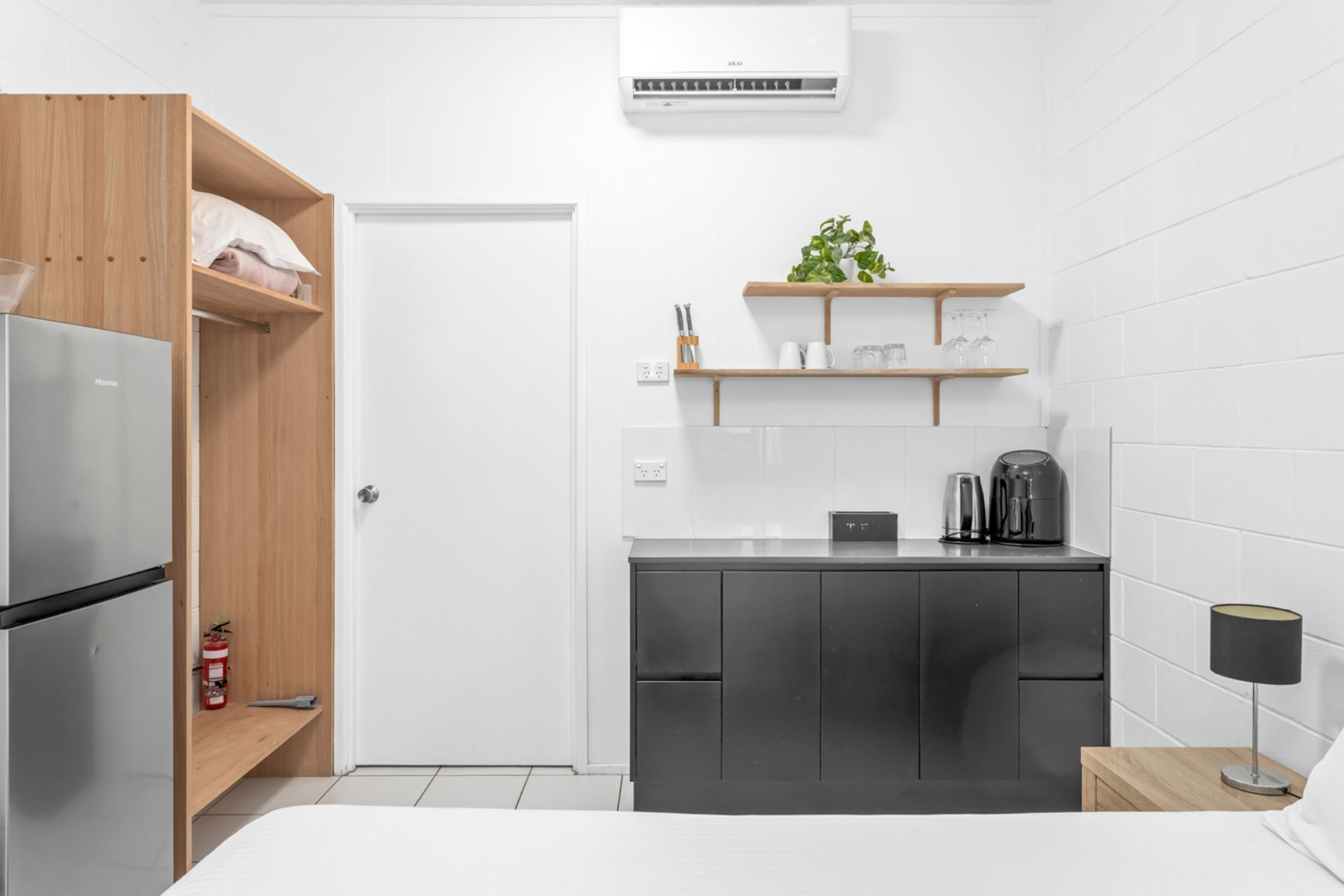 Eine kleine Küche mit Kühlschrank, Kaffeemaschine und einem Regal mit Küchenutensilien.