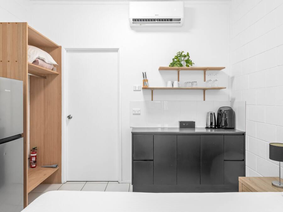 Eine kleine Küche mit Kühlschrank, Kaffeemaschine und einem Regal mit Küchenutensilien.