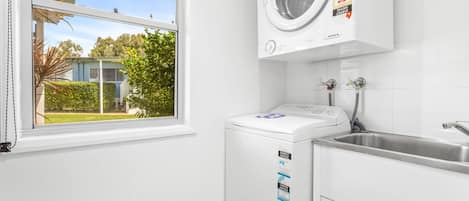A laundry room with a front-loading washing machine, a dryer, and a sink.
