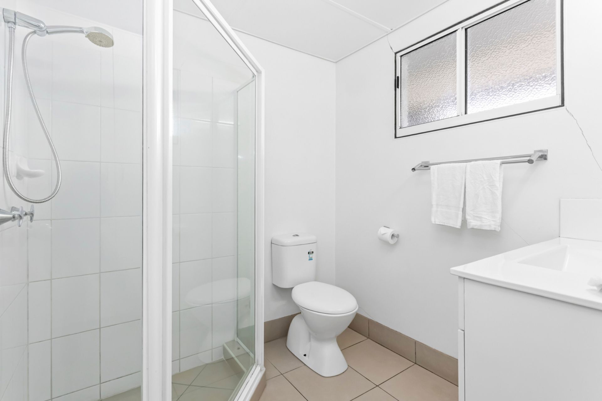 A modern bathroom with a glass shower enclosure, a toilet, and a sink.
