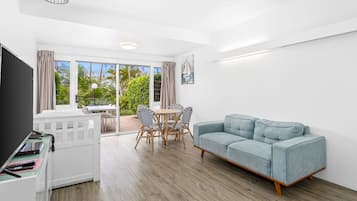 A modern living room with a sofa, a dining table, and a TV stand.