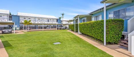 A residential area with multiple two-story buildings, a well-maintained lawn, and a clear sky.