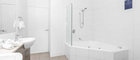 Een moderne badkamer met een ruime badkuip, een aparte douche en een wastafel met spiegel.