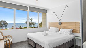 A modern bedroom with a large window, a bed, a chair, and a bedside table. - Rosslyn Bay Resort (Rosslyn)