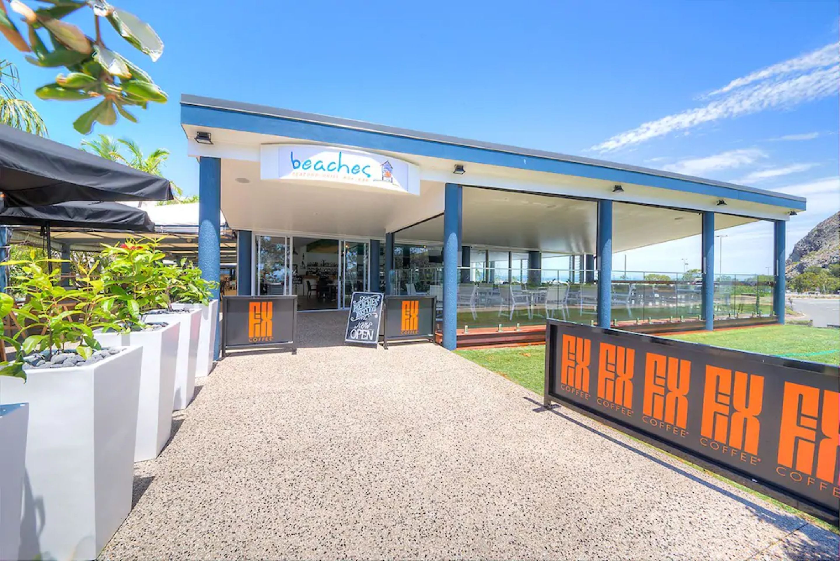 Un cafè a la vora de la platja amb un disseny modern, zones d'estar a l'exterior i vista despejada del mar.