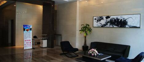 A modern lobby with a reception desk, seating area, and a large abstract painting.