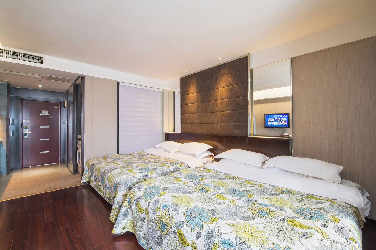 A hotel room with a large bed, a television, and a door leading to a hallway.