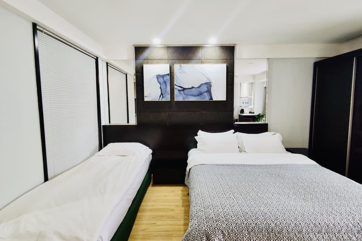 A hotel room with two single beds, a large mirror, and artwork on the wall.