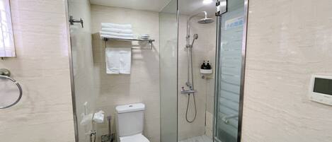 Un baño moderno con ducha de vidrio, inodoro y barra para toallas.