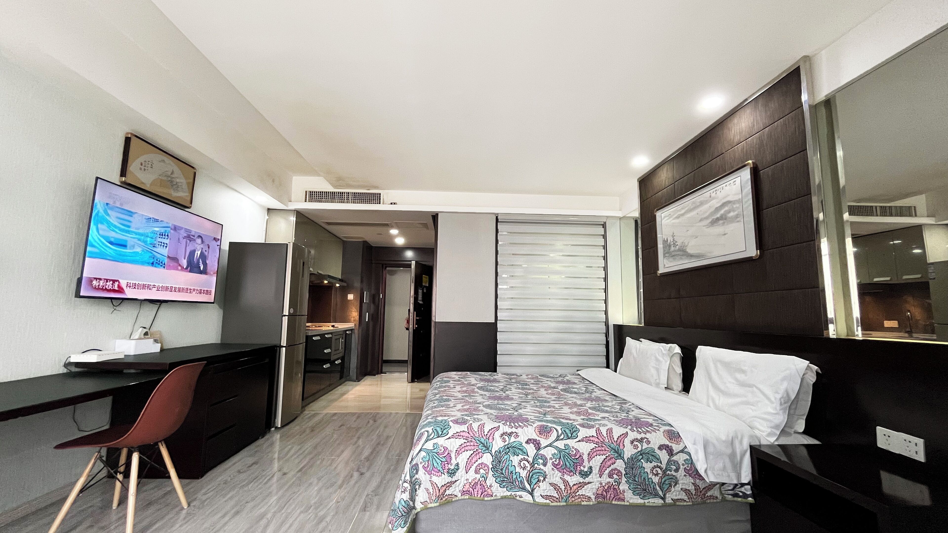 Una habitación de hotel moderna con una cama, un escritorio, un televisor y un guardarropa.