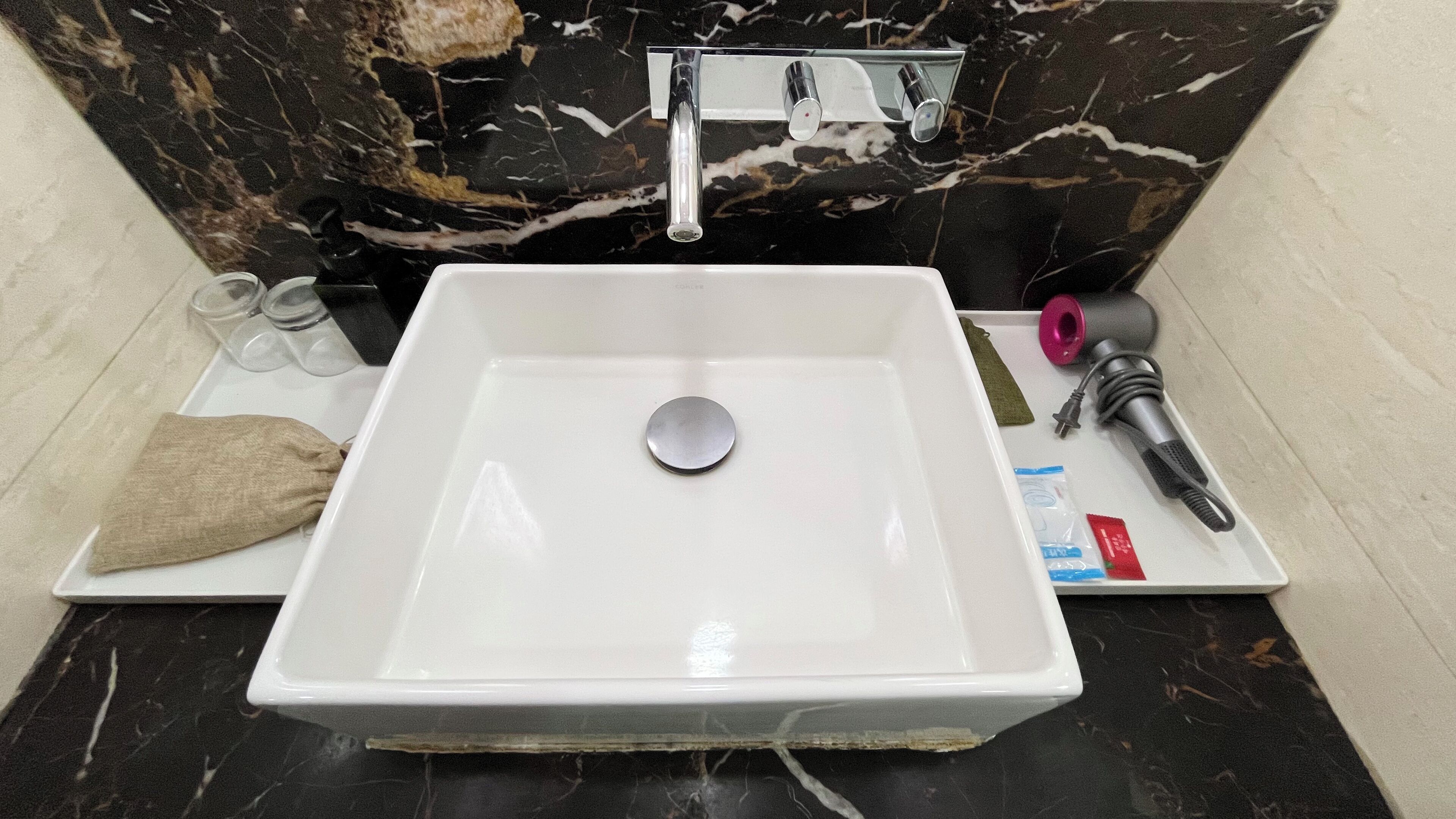 A bathroom with a white sink, a marble backsplash, and a towel on the counter.