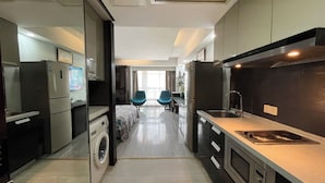 A modern kitchen with a built-in oven, a sink, and a washing machine. There is a dining area with two chairs and a table.