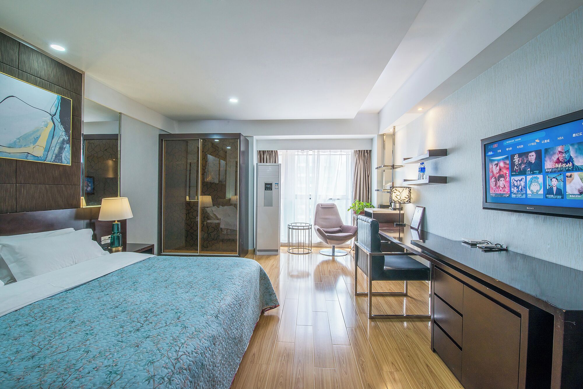Una habitación de hotel con cama, escritorio, silla, televisor y armario.