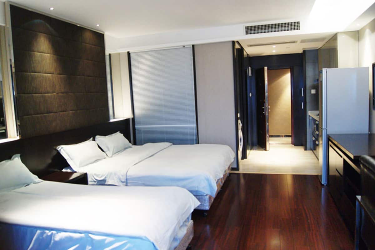 Une chambre d’hôtel avec deux lits, un bureau et un dressing.