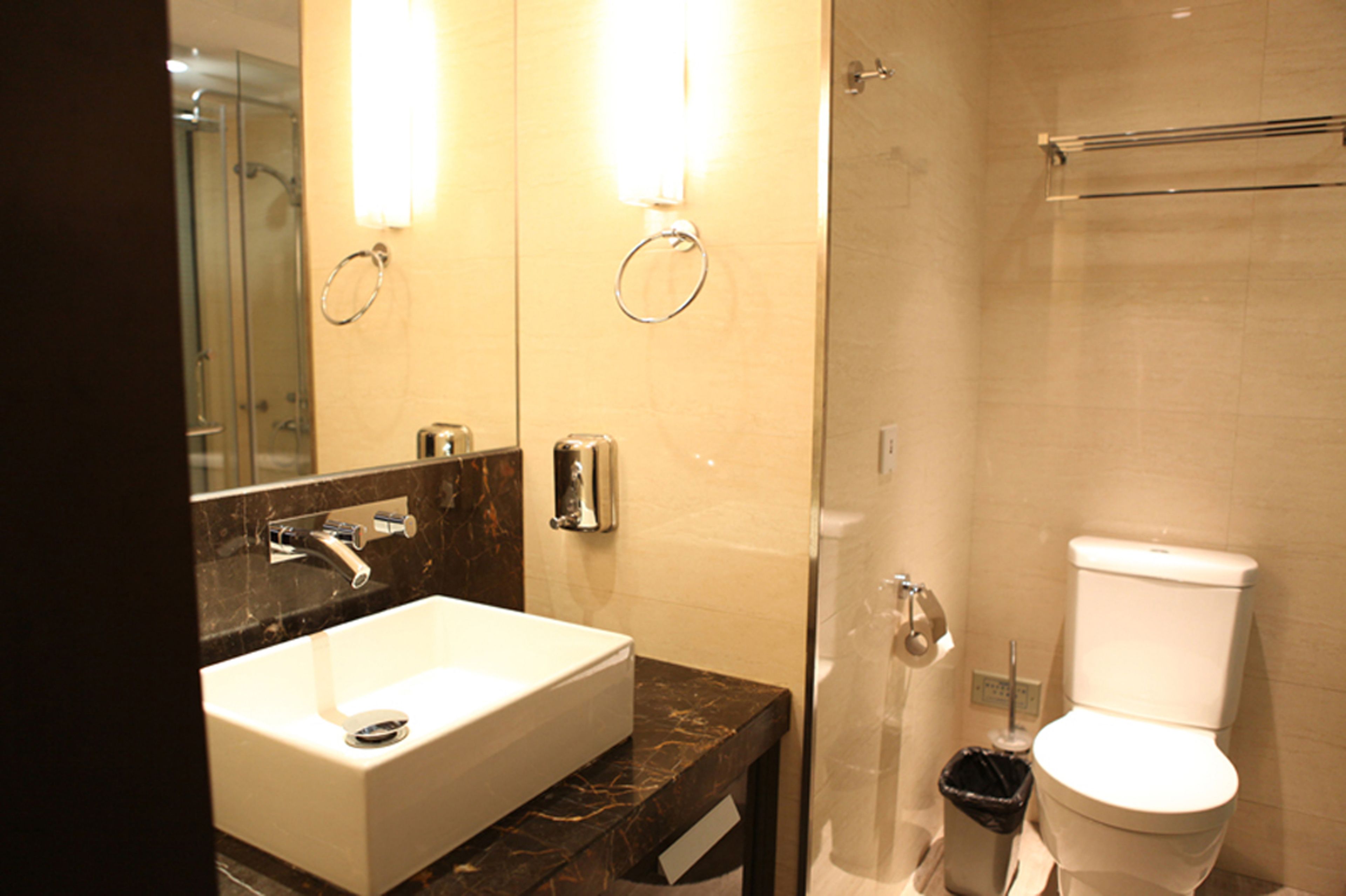 A modern bathroom with a marble sink, a glass-enclosed shower, and a toilet.