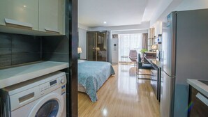 Ein modernes Hotelzimmer mit Bett, Waschmaschine, Küchenzeile und Bad.