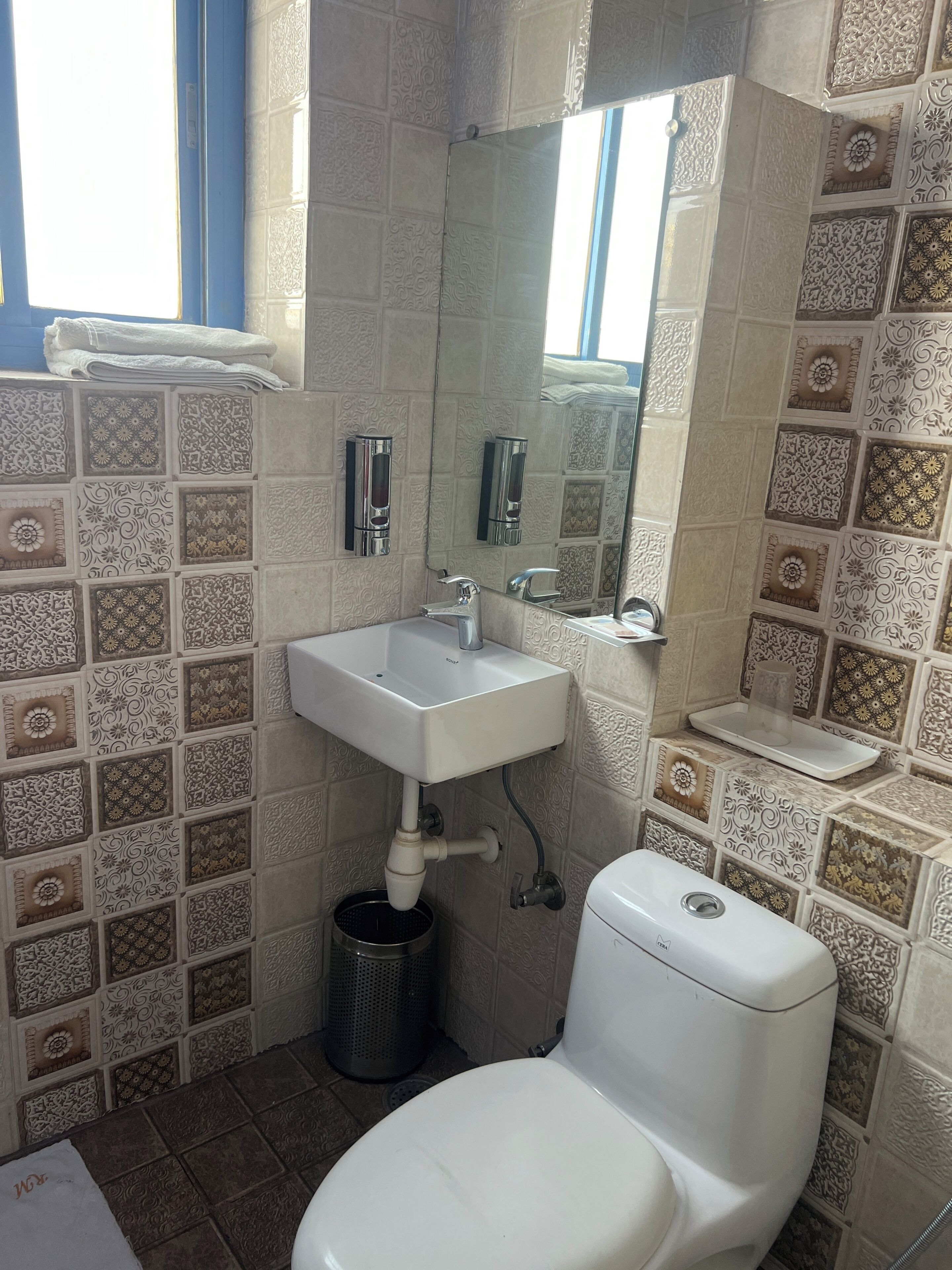 Een badkamer met een wit wastafel, toilet en afvalbak.
