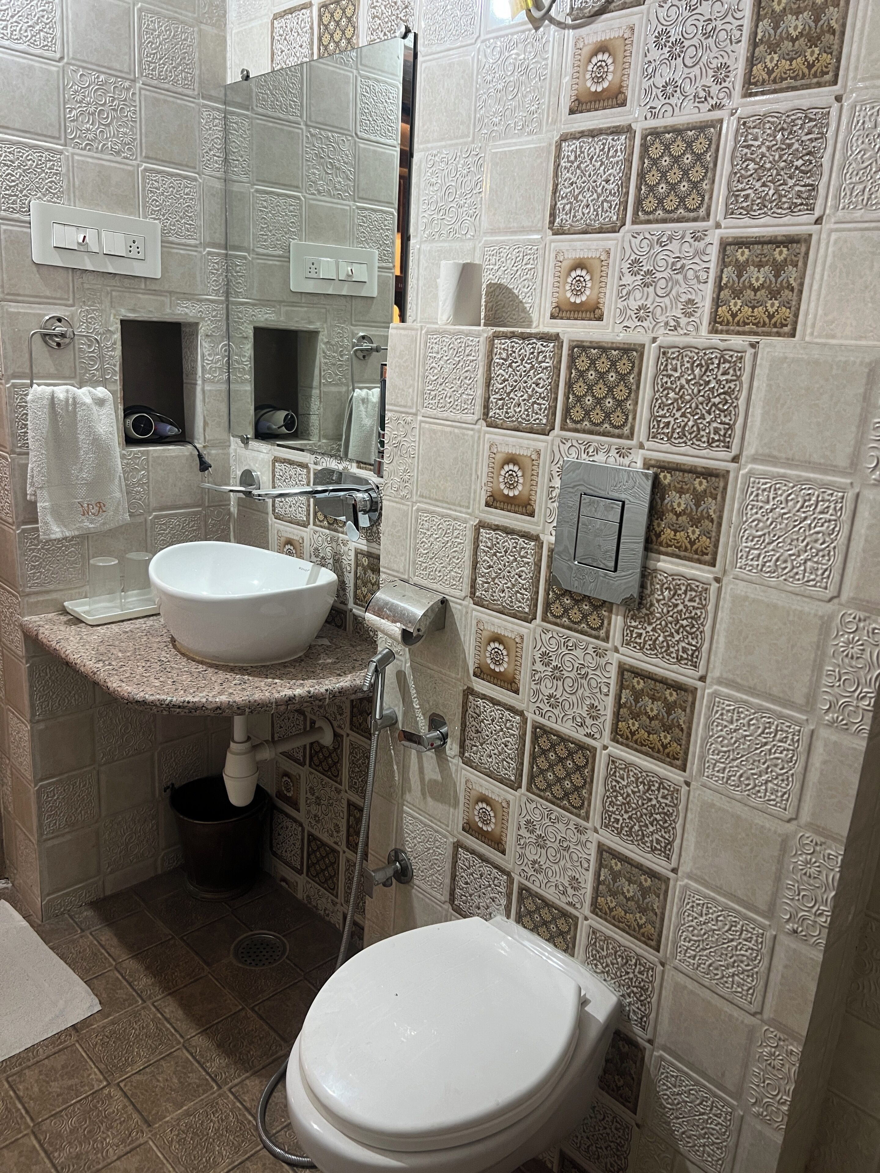 Un baño con lavamanos, espejo, toallero y retrete.
