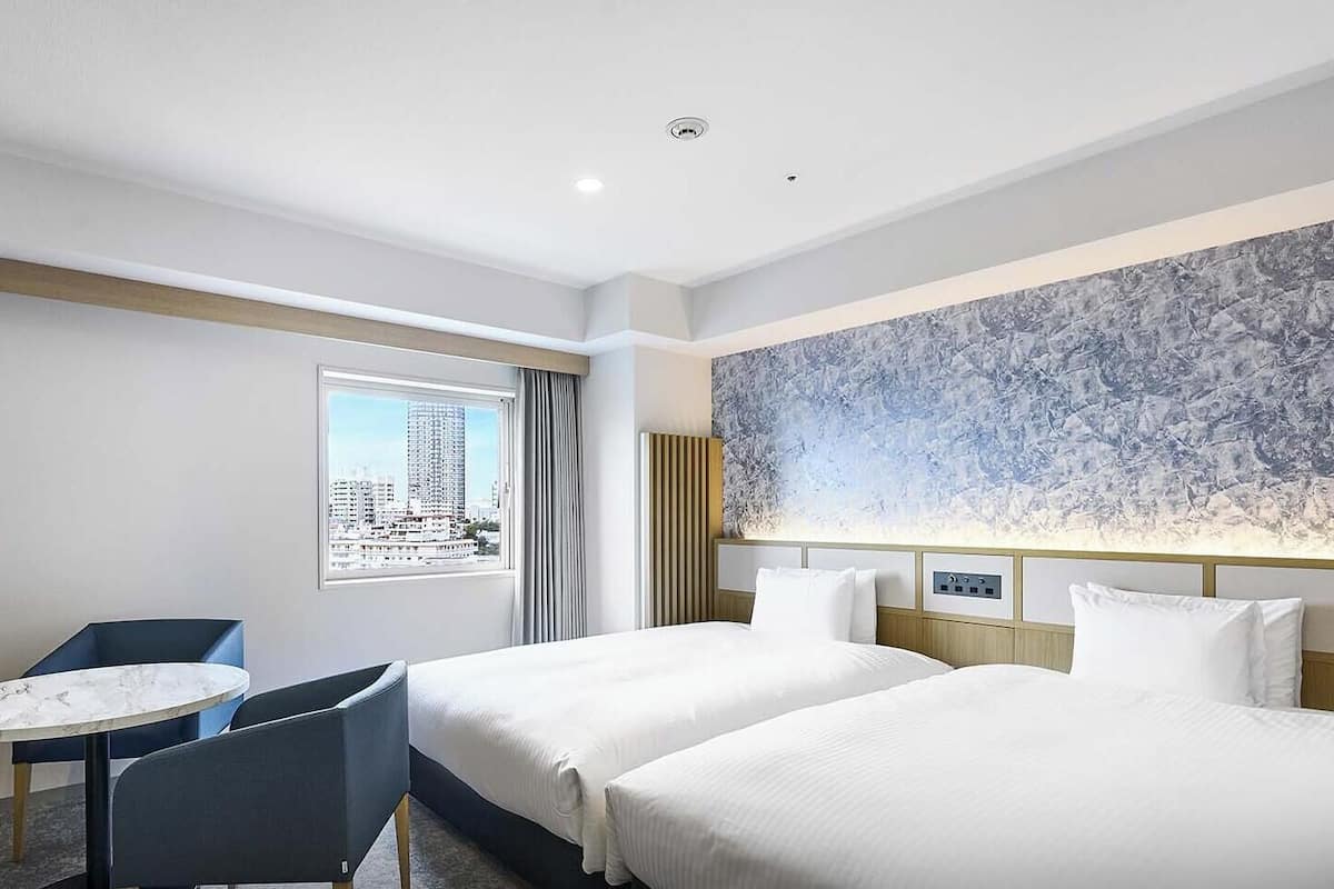Una habitación de hotel con dos camas, una mesita y una silla.