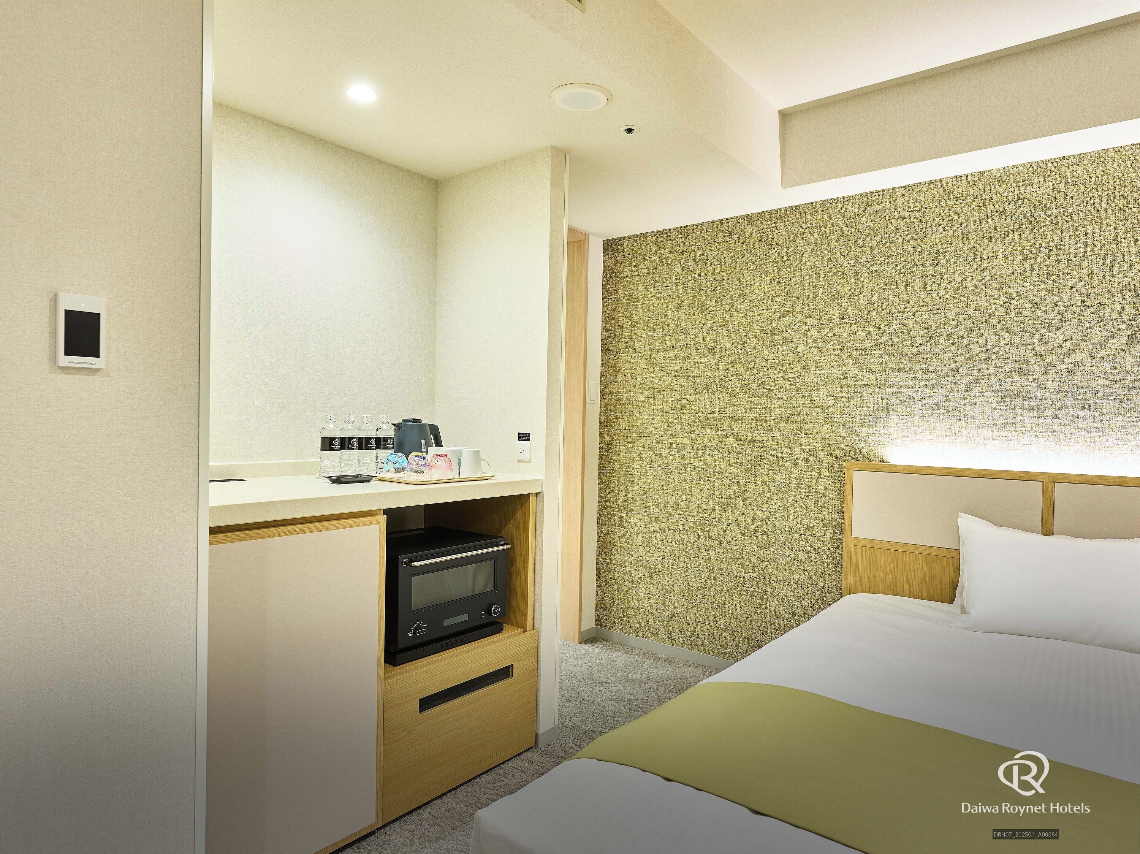 Ein Hotelzimmer mit Bett, Schreibtisch, Kaffeemaschine und Mikrowelle.