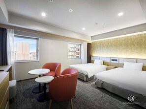 Ein Hotelzimmer mit zwei Betten, einem Schreibtisch, einem Stuhl und einem kleinen Tisch.