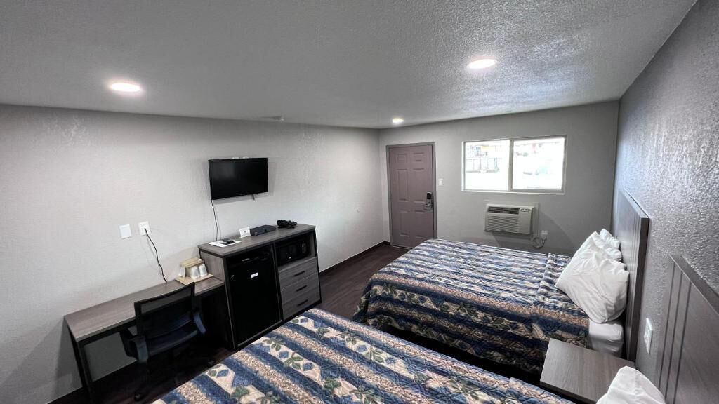 A room with two beds, a desk, a television, and a window with a view.
