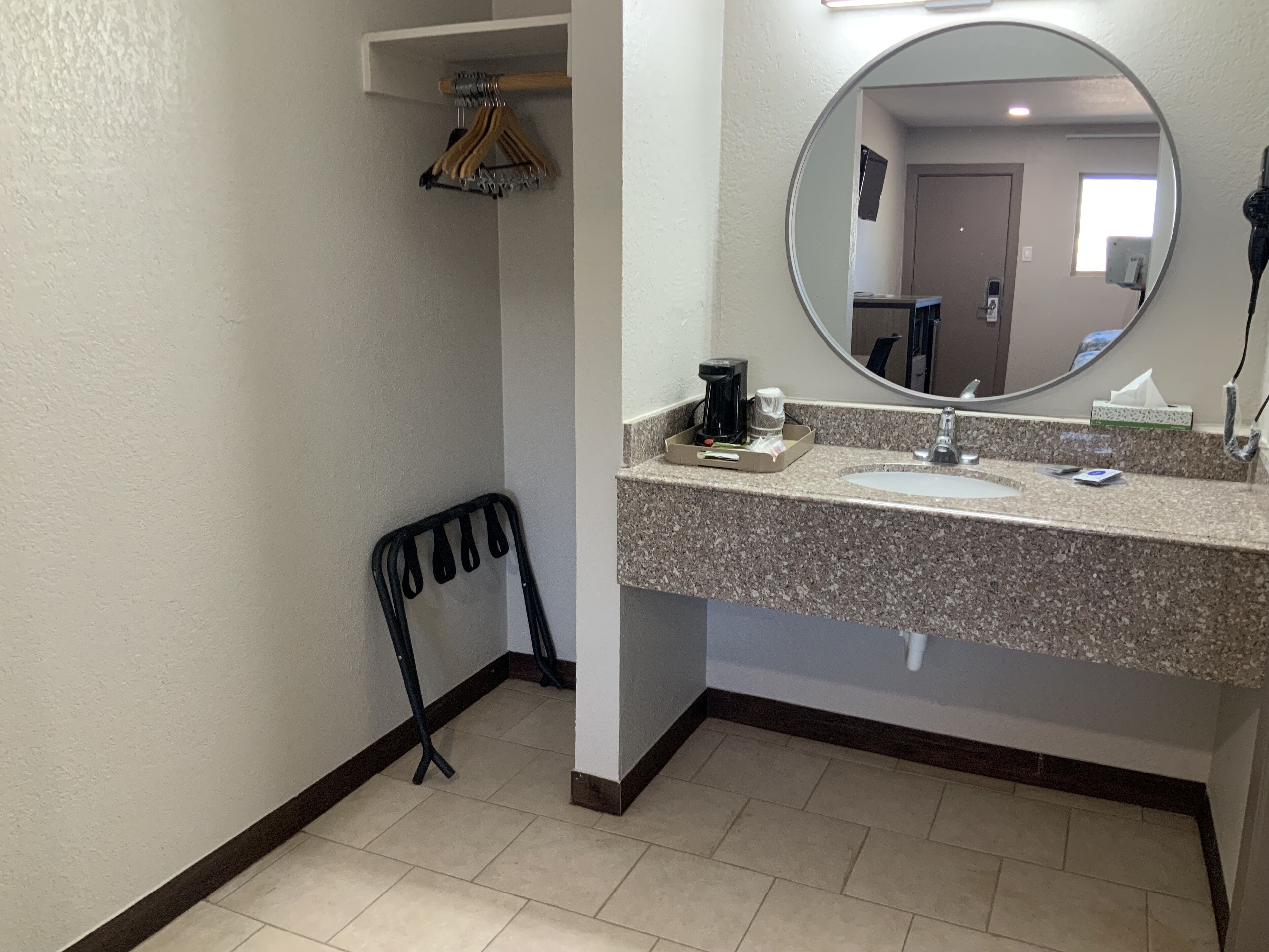 A bathroom with a sink, mirror, and a chair.