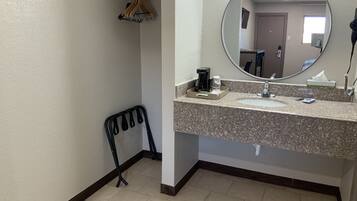 A bathroom with a sink, mirror, and a chair.