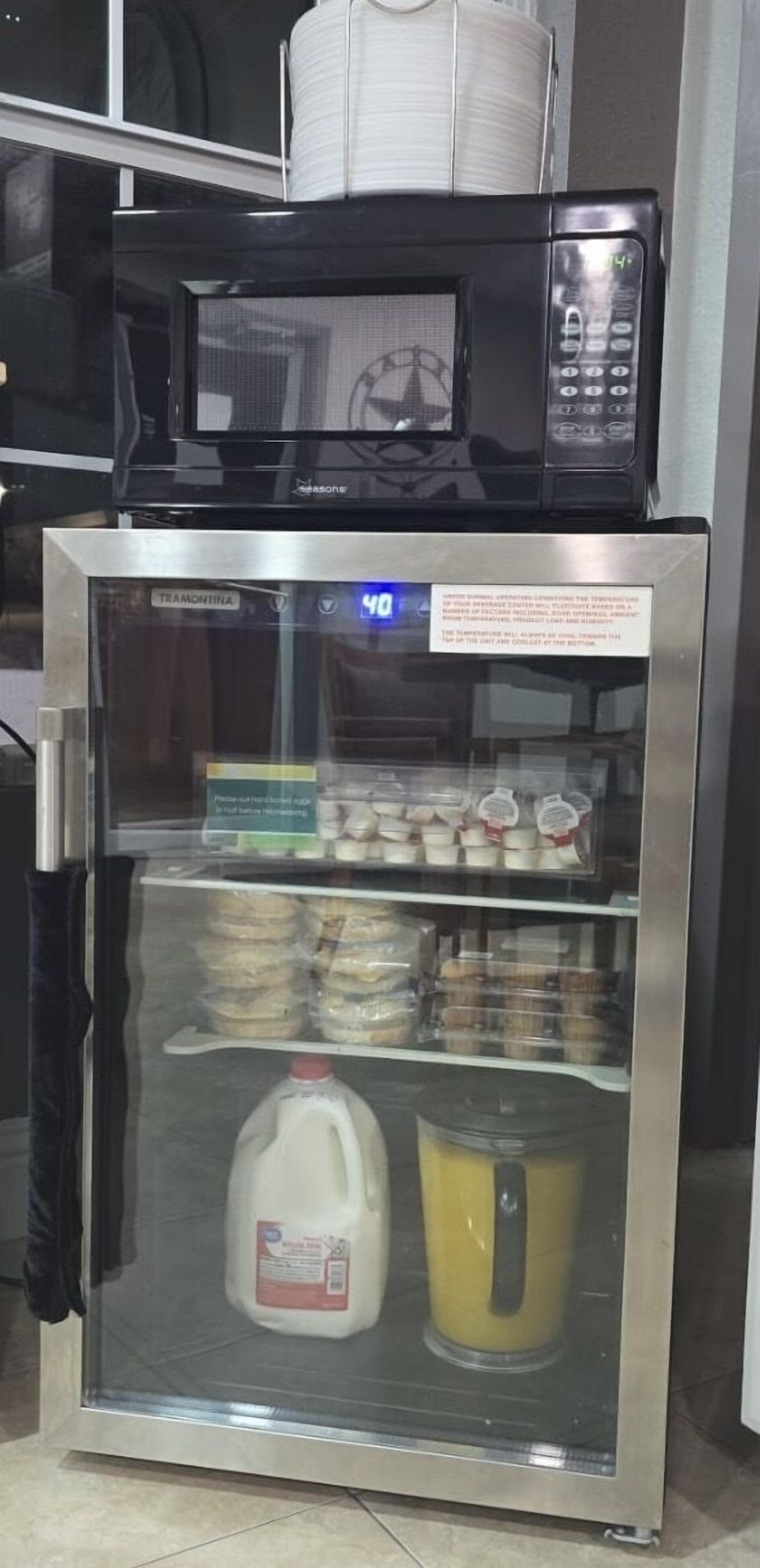 A refrigerator with a glass door, containing milk and a container of orange juice.