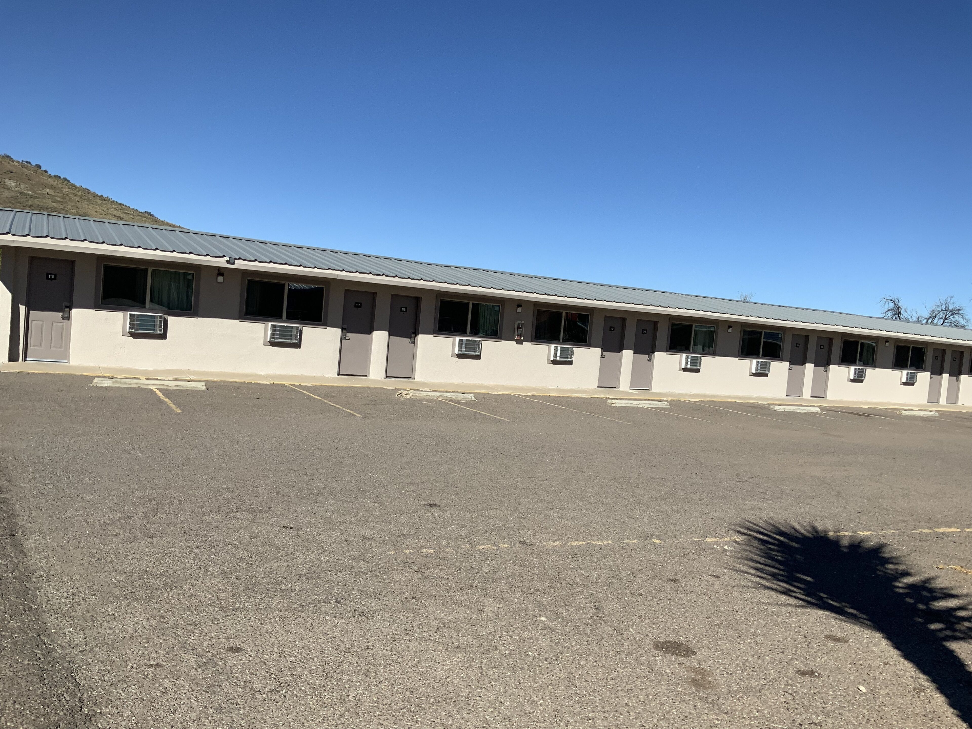 A long, single-story motel with a row of rooms, each with a door and a window.