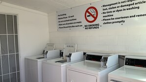 A laundry facility with multiple washing machines and a no-smoking sign. - Value Lodge (Alpine)