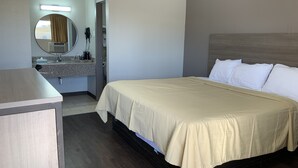 A hotel room with a bed, a bedside table, a mirror, and a bathroom with a sink and towel rack. - Value Lodge (Alpine)
