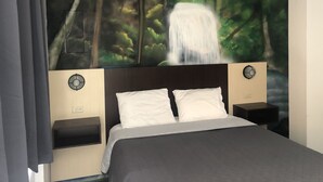 Ein Schlafzimmer mit einem Bett, zwei Nachttischen und einem großen Wandbild mit Waldmotiven.