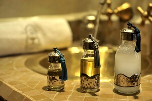 Tre bottiglie di vetro con tappi metallici e nappine, posizionate su una superficie piastrellata.